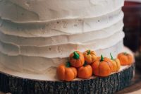 a white buttercream wedding cake with mini sugar pumpkins on top and around it is a cheerful idea for a fall rustic wedding