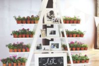 a white ladder with blooming flowers in pots and family photos and a chalkboard sign