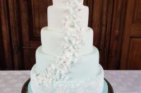 a white to light green ombre wedding cake decorated with lace and with white and green butterflies climbing it