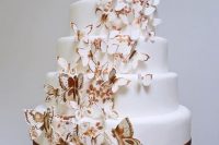 a white wedding cake decorated with painted amber blooms and with lots of butterflies climbing up the cake is wow