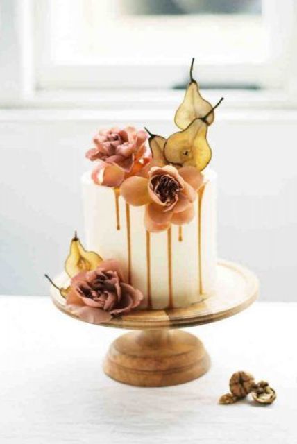 a white wedding cake with caramel drip, dusty pink blooms and dried pear slices is a cool idea for the fall