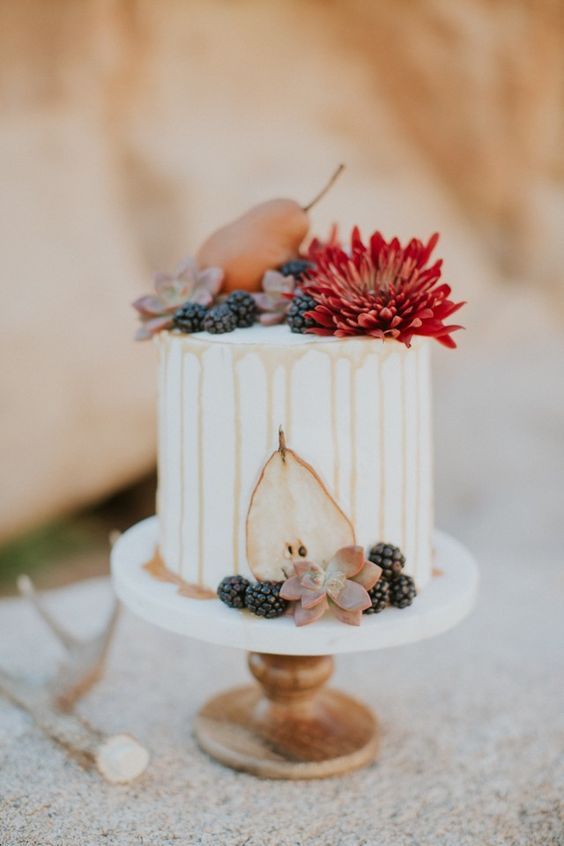 a wihte buttercream wedding cake with caramel drip, a bold bloom, pears and succulents, blackberries is a cool idea for the fall