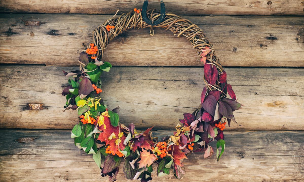 A wine wreath covered with greenery, dark foliage, berries and bright leaves is an all natural fall wedding idea