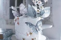 an artful wedding cake decorated with faux blooms, butterflies on sticks is a lovely and very tender idea of a wedding dessert