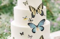 an elegant white wedding cake with yellow and blue butterflies is a chic and stylish idea that catches an eye