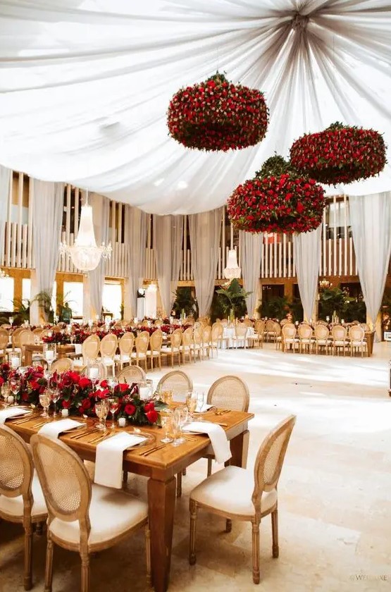 an exquisite Valentine's Day wedding venue with jaw dropping red rose chandeliers and a red rose table runner with greenery