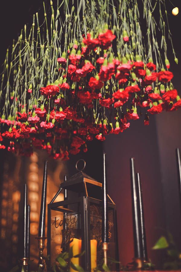 an overhead red flower wedding installation will substitute a wedding centerpiece and paired with black candles will create a wow effect