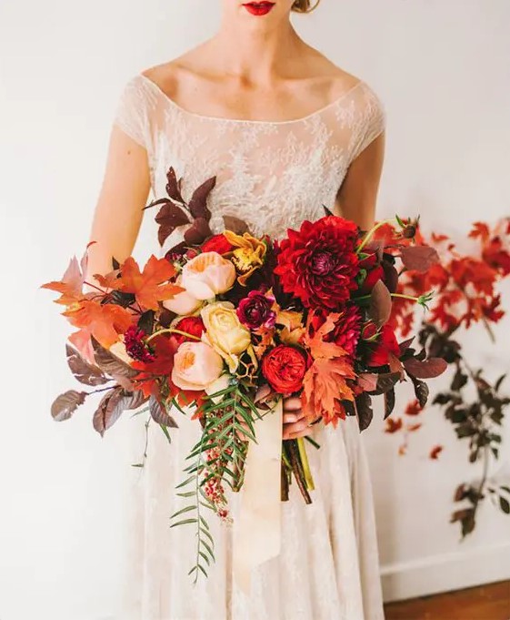 an oversized colorful wedding bouquet with various fall leaves, cascading greenery and bright blooms