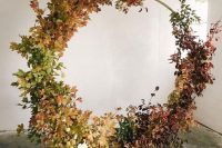 an oversized fall wedding wreath covered with leaves and dried foliage with an ombre effect is a fantastic idea for a rustic wedding