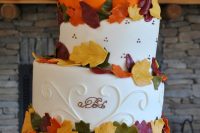 an oversized white buttercream and pumpkin wedding cake with sugar leaves is a fun idea for a fall rustic wedding