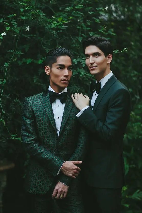 beautiful green pantsuits, a dark green one and a green printed one, white shirts and black bow ties for a cohesive couple's look
