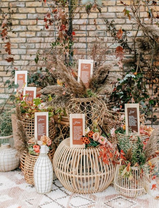 beautiful outdoor fall wedding decor with rattan tables and ottomans, fall foliage and blooms, pampas grass and signage