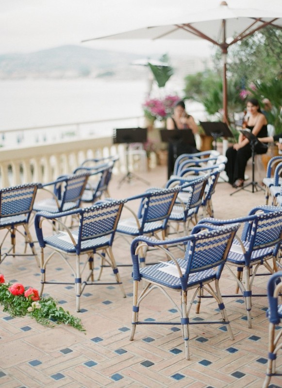 blue woven ceremony chairs matching the color of the surrounding Mediterranean Sea   a perfect idea for a seaside wedding