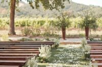 dark-stained benches, the aisle decorated with white petals, white blooms and greenery are  lovely combo for many outdoor weddings