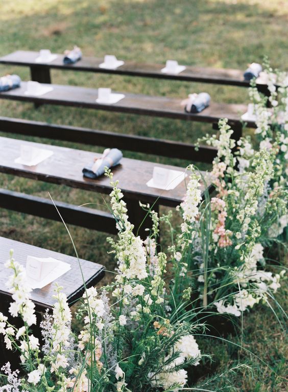 dark-stained benches with greenery and neutral blooms lining up the aisle are a romantic idea for a garden wedding