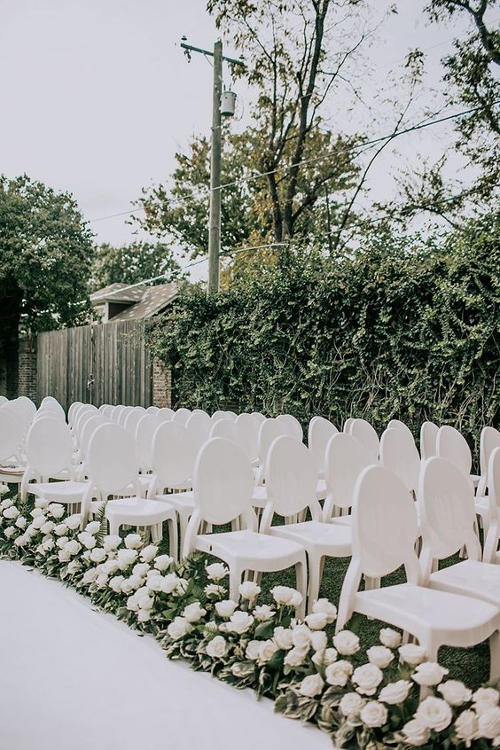 elegant vintage inspired all white chairs and white roses along the aisle are great for a modern and sophisticated wedding