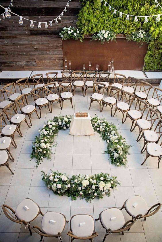 elegant white chairs arranged in circles, white blooms and greenery are a chic and lovely idea for a stylish wedding ceremony