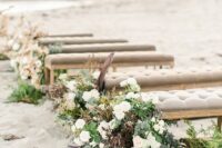 grey upholstered benches decorated with greenery, neutral and dark blooms are a stylish idea for a chic beach wedding