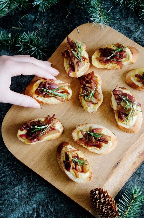 hummus and caramelized onion crostini with soem rosemary on top are a delicious idea