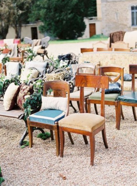 mismatching rustic benches and chairs with various upholstery, greenery and moss are a great idea for a rustic wedding