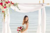 a beach bamboo wedding arch with white tulle and bright and neutral blooms to decorate a corner