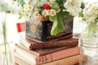 a bright summer wedding centerpiece with books, a vintage tin can and fresh blooms in it