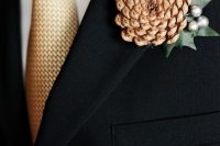 a chic pinecone, leaf and silver berries wedding boutonniere is a refined accent for a modern winter groom