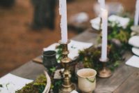 a chic woodland wedding table with a moss and greenery runner, pinecones, antlers and candles is a great idea for the fall
