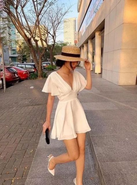 a classy summer bride-to-be look with a plain A-line mini dress with a deep neckline and short sleeves, white heels, a black clutch and a straw hat