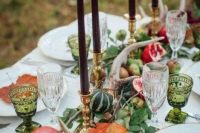 a fall wedding tablescape with a harvest feel, with greenery, antlers, pumpkins and pomegranates plus burgundy candles
