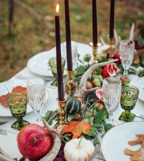 a fall wedding tablescape with a harvest feel, with greenery, antlers, pumpkins and pomegranates plus burgundy candles