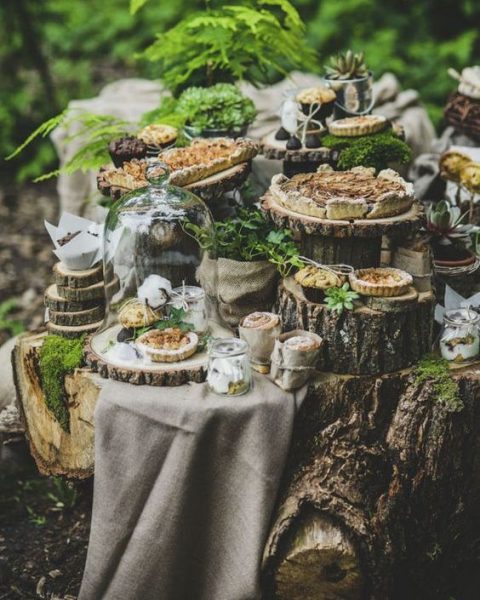 a forest wedding dessert table with lots of tree stumps, slices and delicious pies and tartlets and greenery