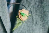 a funny wedding boutonniere of fern, a leather badge and a green dinosaur is a bright and cool idea to go for