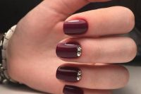 a glossy burgundy manicure with shiny gold embellishments is a lovely refined option to rock