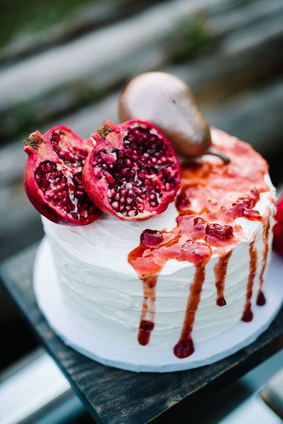 a gorgeous fall wedding cake with pomegranates, a pear and some berry compote on top is amazing for a fall wedding