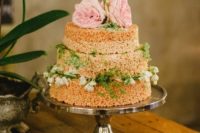 a krispie rice wedding cake with greenery, white and pink blooms is a stylish and timeless idea
