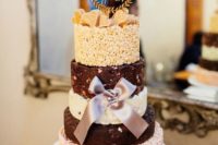 a krispie rice wedding cake with white and dark chocolate tiers, edible hearts on top, a creative topper and a silk bow