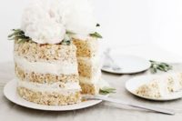 a krispie rice wedding cake with white cream and fresh white peonies and greenery on top looks very elegant