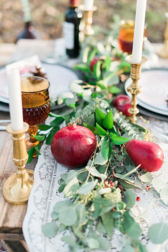 a lush and bold wedding table runner of greenery, pears and pomegranates, berries and thin and tall candles is amazing for the fall