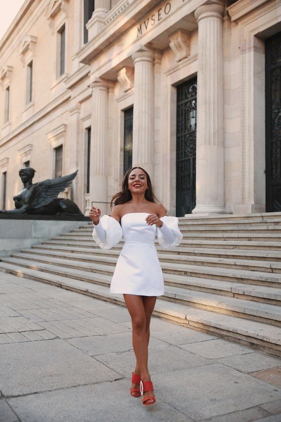 a modern plain white off the shoulder mini dress with puff sleeves, red shoes for a bold and sexy bride-to-be look
