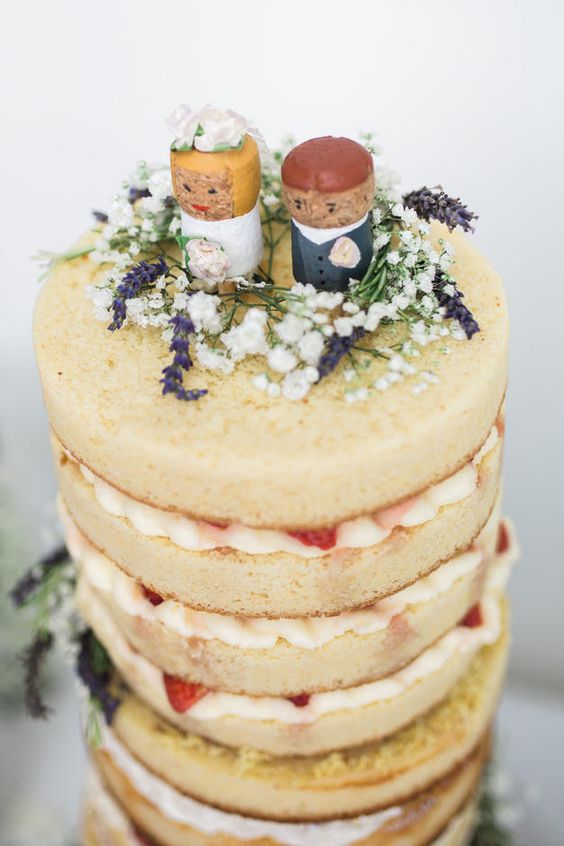 a naked wedding cake with strawberries and wild blooms plus cork cake toppers in bright colors