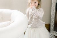 a neutral braided sweater and a white tutu skirt for a lovely and comfy winter flower girl look