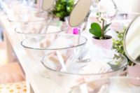 a pastel spa bridal shower setting with beautiful potted blooms and greenery, mirrors and glass bowls, treatments and pillows
