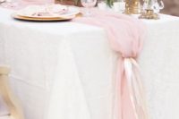 a pink tulle table runner adds tenderness to the table and matches the wedding centerpiece with pink blooms