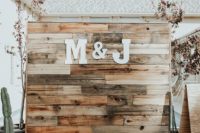 a rustic boho wedding backdrop made of stained pallet wood and monograms plus cacti around is a trendy idea
