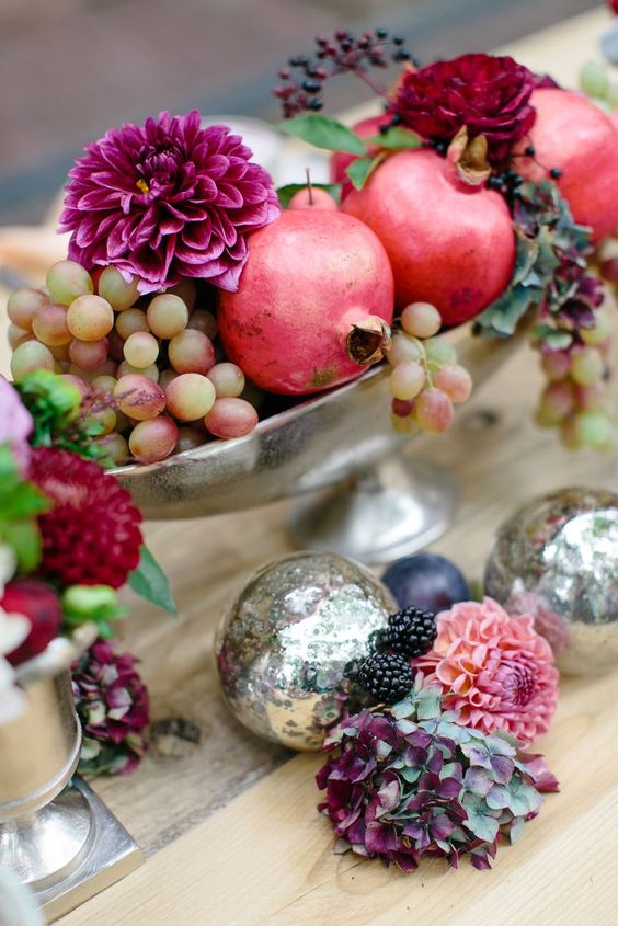 a silver bowl with grapes, pomegranates, fuchsia and deep red blooms and berries is a beautiful fall wedding centerpiece