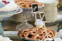 a simple summer wedding pie bar with plates, chic glass stands and chalkboard topper and some blooms