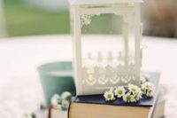 a simple wedding centerpiece of a couple of books, some chamelias, a white lantern