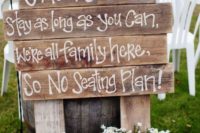 a simple wedding ceremony space sign made of pallet wood and with potted blooms in buckets around