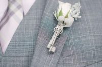 a small and pretty wedding boutonniere of a vintage key, a white rose and pale greenery is a lovely accessory for a groom or a groomsman